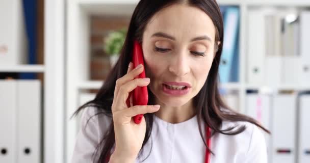 Vrouwelijke arts praten op mobiele telefoon in kliniek 4k film slow motion - Video