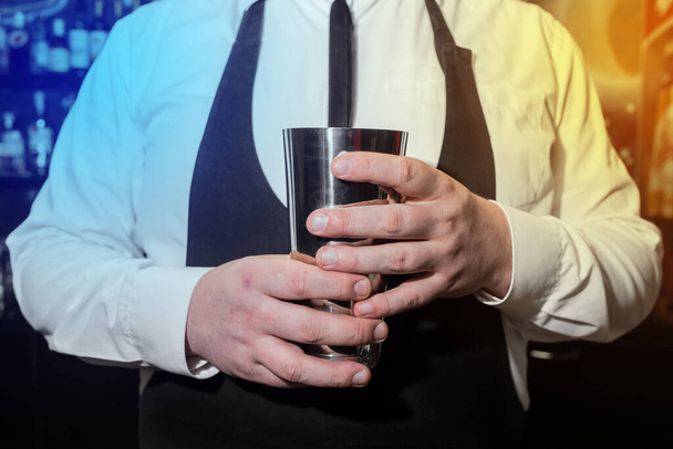 Руки профессионального бармена держат в руках инструмент для смешивания и изготовления шейкерных коктейлей. - Фото, изображение