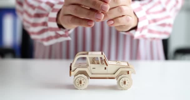 Vrouwelijke handen knuffelen en beschermen speelgoed houten auto 4k film slow motion - Video