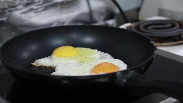 kuchař sype koření na míchaná vajíčka na sporáku - Záběry, video