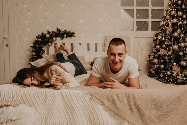 casal homem e mulher mentira na cama quarto perto da árvore de Natal. - Foto, Imagem