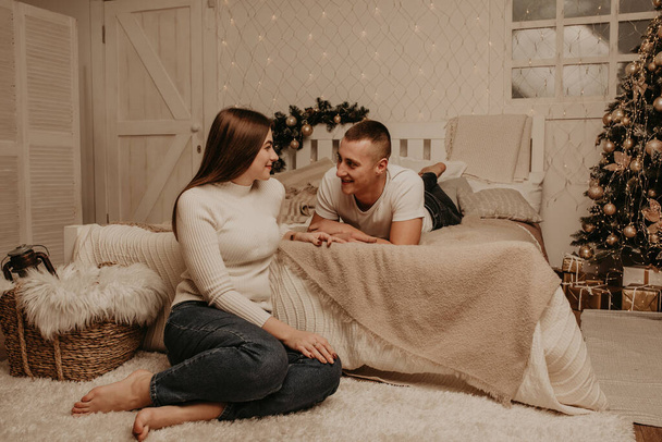 couple homme et femme couché sur le lit chambre près de l'arbre de Noël. - Photo, image