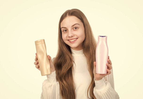 onnellinen teini tyttö esittää shampoo tai hiukset kehon hoitoaine pullo eristetty valkoinen, keratiini - Valokuva, kuva
