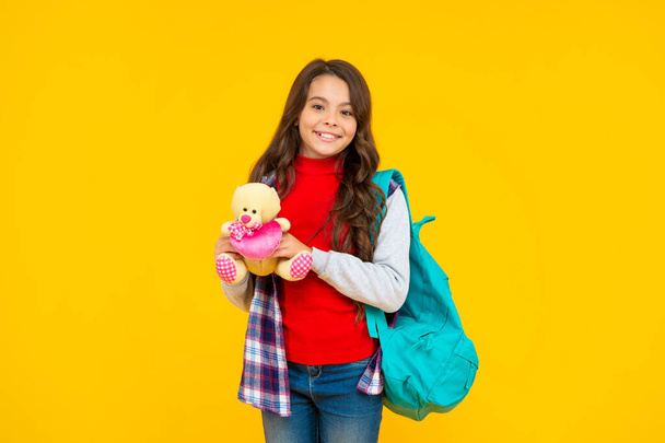 cheerful child casual style with backpack and toy on yellow background, school - Foto, Imagem
