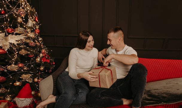homem e mulher casal no amor abrir caixas de presente desamarrar um arco perto da árvore de Natal - Foto, Imagem