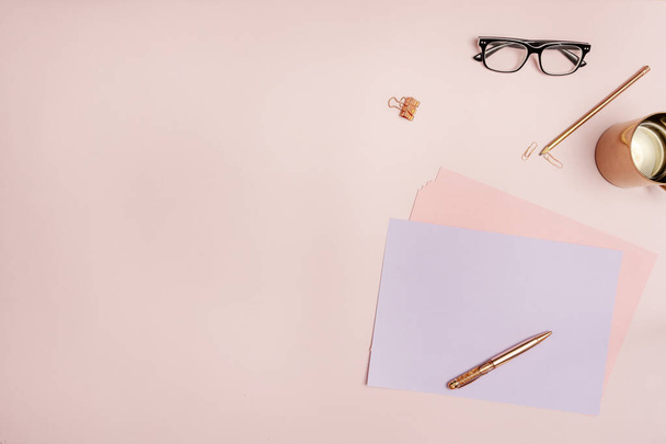 Asetelma top näkymä kirjailija pastelli vaaleanpunainen sävyjä kupari kannu, musta lasit ja paperit - Valokuva, kuva