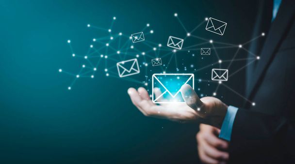 Επιχειρηματίας χέρι κρατώντας e-mail εικονίδιο επιστολή σε ένα περιβάλλον αφής οθόνη, εικονικό ταχυδρομικό φάκελο, την έννοια του spam email, το διαδίκτυο και τη δικτύωση, Επικοινωνήστε μαζί μας ενημερωτικό δελτίο e-mail και να προστατεύσει την προσωπική σας. - Φωτογραφία, εικόνα