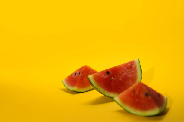 Widok z bliska na świeże dojrzałe plastry arbuza izolowane na pomarańczowym tle. Owoce tropikalne, zdrowe odżywianie i letnia koncepcja tła. - Zdjęcie, obraz