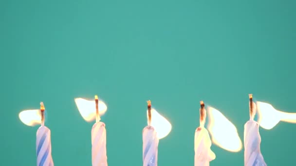 Happy Birthday concept Made of Burning Colorful Candles on blue or turquoise background. Blowing out five years anniversary birthday candles. Slow motion full HD video - Footage, Video