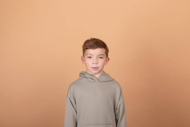 Genç bir çocuğun duygusal portresi. Çekici okul çocuğu. Güzel çocuk. açık kahverengi arkaplanda - Fotoğraf, Görsel