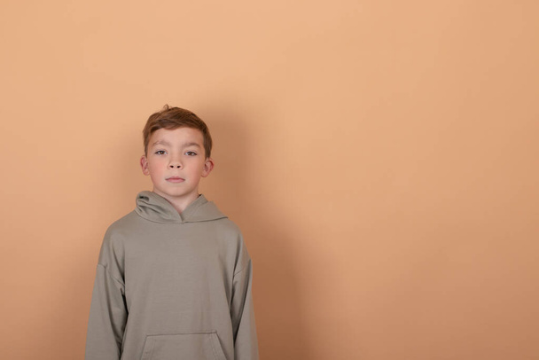 emotional portrait of a young boy teenager. charming school boy. beautiful kid. on light brown background - Photo, Image