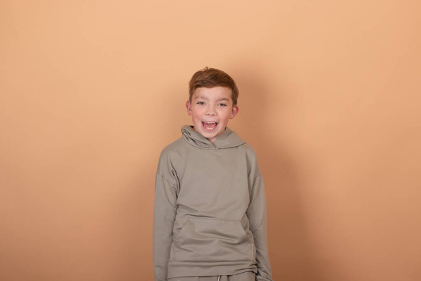 Genç bir çocuğun duygusal portresi. Çekici okul çocuğu. Güzel çocuk. açık kahverengi arkaplanda - Fotoğraf, Görsel