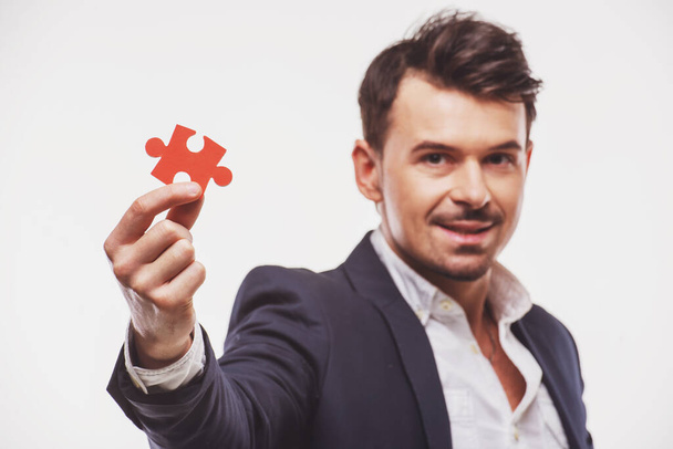 Handsome businessman showing small jigsaw puzzle over white background. - Fotografie, Obrázek
