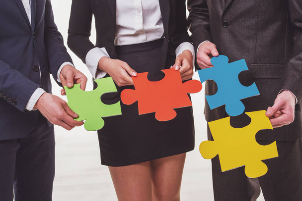 Close-up of business people wanting to put pieces of puzzle together. - Photo, Image
