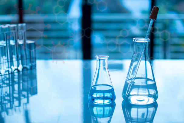 Concepto de experimento químico en laboratorio científico Dos frascos científicos de diferentes tamaños contienen diferentes sustancias químicas. Los productos químicos están en muchos tubos de vidrio que se colocan en la mesa y borrosa. - Foto, imagen