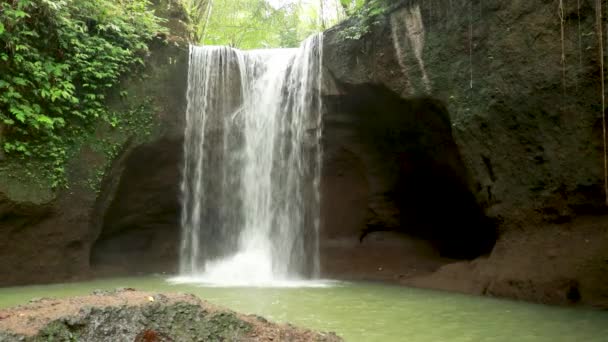 Piękny wodospad ukryty w tropikalnej dżungli deszczowej z bambusową tratwą na tle dekoracje kamień rzeźbiarski w stylu Majów. 4K Podróże w dzikiej przyrodzie - Materiał filmowy, wideo