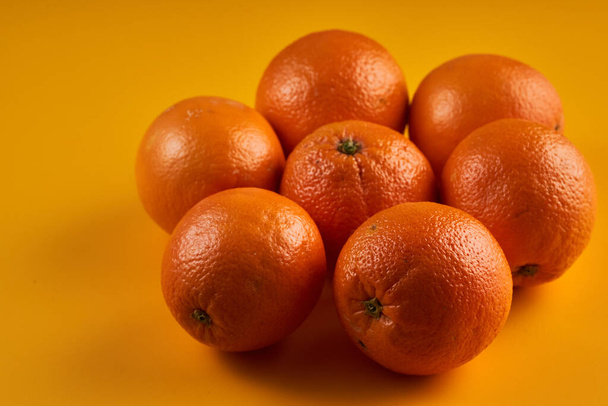 Fresh oranges on a yellow background, closeup shot - Foto, afbeelding