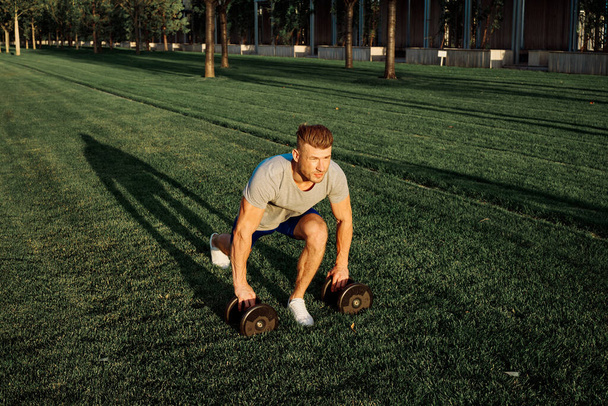 athletic man in the park workout exercise dumbbells - Foto, Imagem