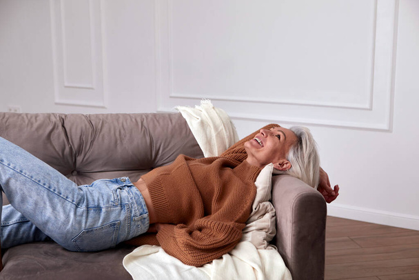 Pozytywne kobiety w średnim wieku śmiejące się na kanapie - Zdjęcie, obraz