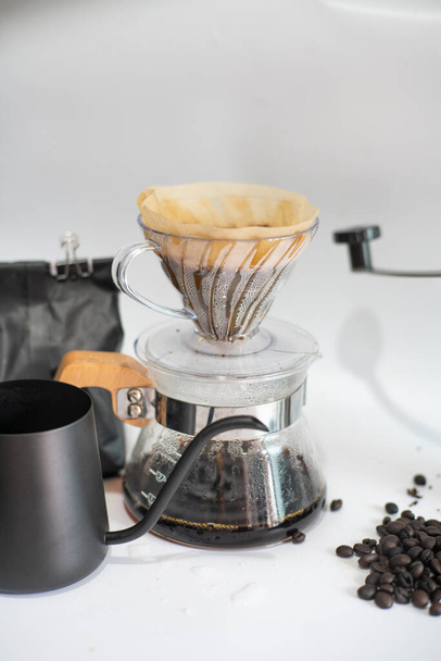 Крапелька заварювання кави на папері фільтрована заливка води над обсмаженою кавовою квасолею на білому фоні
 - Фото, зображення