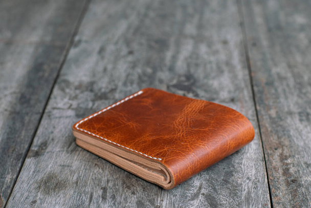 Bräunlich braunes Leder doppelte Brieftasche auf Holz Hintergrund DIY handwerkliche Arbeit - Foto, Bild