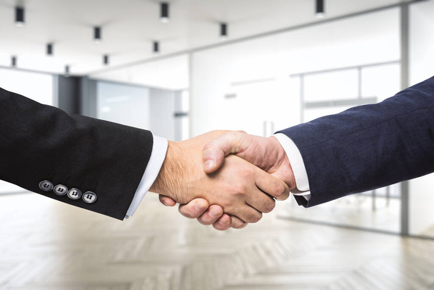 Two businessmen shake hands on the background of modern furnished office, partnership concept, close up - Фото, зображення