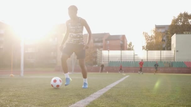 Fiatal afro-amerikai női focista és edzés a városi stadionban, miközben gyakorolja a cselezést egy labdával - Felvétel, videó