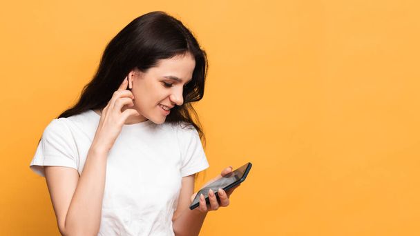 Usmívající se žena drží chytrý telefon, na kterém nahrává zvukové zprávy nebo mluví v audio chatu, stojící na žlutém pozadí. Kopie toho místa. Mezera pro text - Fotografie, Obrázek