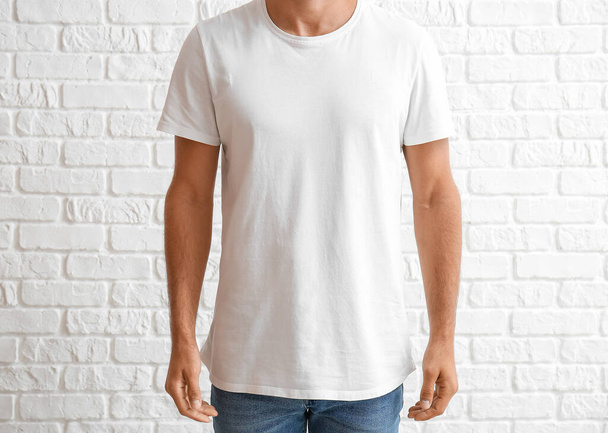 Handsome young man in stylish t-shirt on white brick background - Photo, Image
