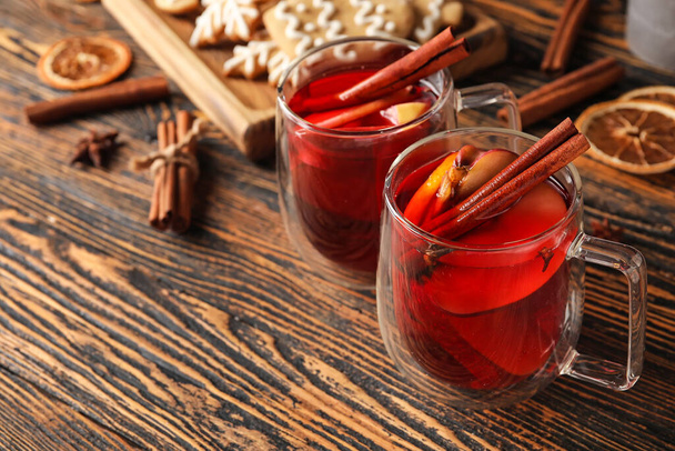Γυάλινα φλιτζάνια νόστιμο τσάι φρούτων με κανέλα σε ξύλινο φόντο - Φωτογραφία, εικόνα