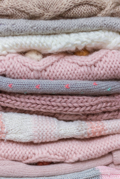 Une pile de chapeaux et de snoods tricotés pour bébés dans les tons beige et rose - Photo, image