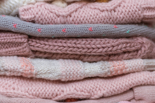 Una pila de sombreros y snoods de punto bebé en tonos beige y rosa - Foto, imagen