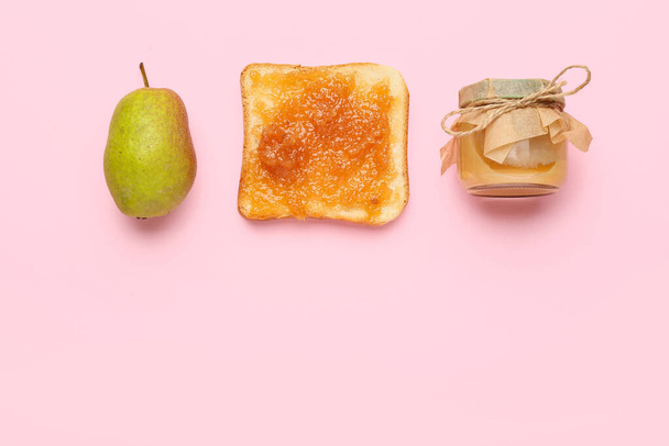 Skleněná sklenice chutné hrušky džem a chlebem na růžovém pozadí - Fotografie, Obrázek
