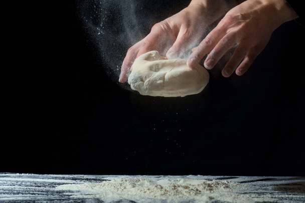 hands prepare the dough on a dark background. homemade dough - 写真・画像