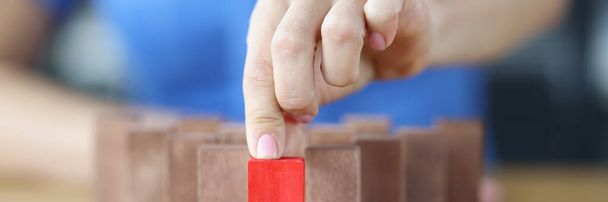 Woman chooses red wooden block among others on wooden table closeup - Foto, Imagen