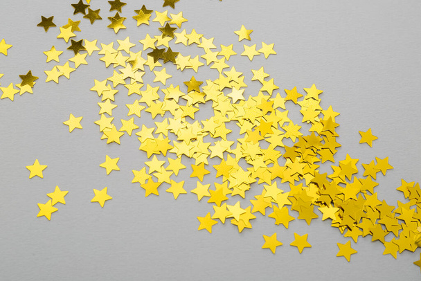 Kultainen konfetti tähtien muodossa harmaalla pohjalla, lähikuva - Valokuva, kuva