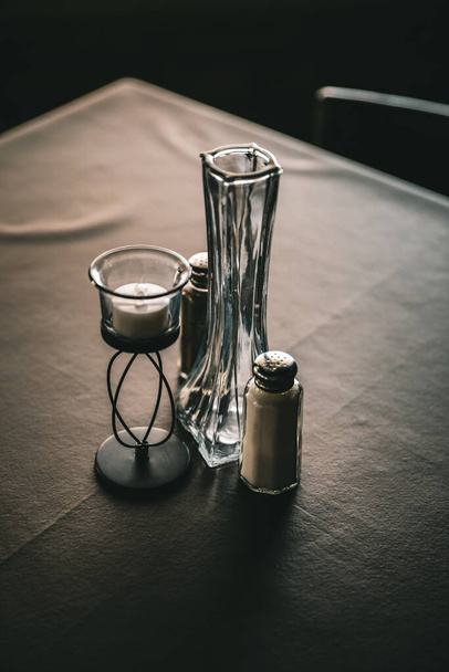 Two salt and pepper containers and a candle on a dinner table - Foto, Bild