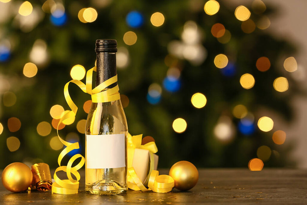 Bottle of champagne with Christmas decor on table against blurred background - Foto, imagen