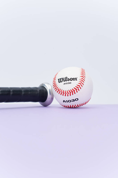 INVERIGO, ITALY - Dec 08, 2021: isolated baseball ball and bat on a lilac background with text space - Photo, Image