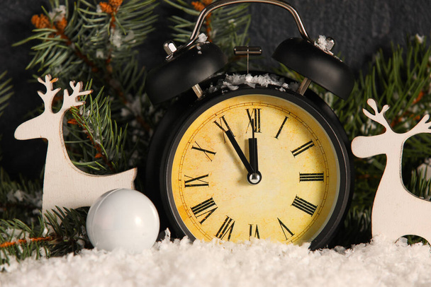 暗い背景を背景に雪の上に目覚まし時計、クリスマスの装飾やモミの枝と組成 - 写真・画像