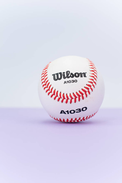 INVERIGO, ITALY - Dec 08, 2021: isolated baseball ball on a lilac background with text space - Fotografie, Obrázek