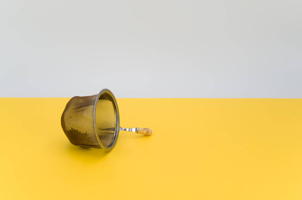 metal tea strainer on a yellow tabletop background with text space - Photo, image