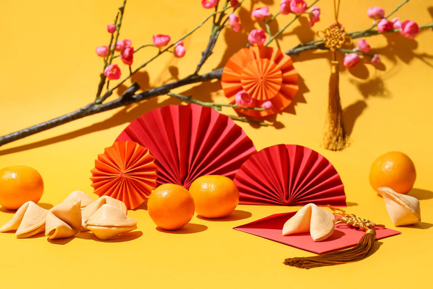 Kompozice s chutnými koláčky štěstí, mandarinkami a čínskou výzdobou na barevném pozadí - Fotografie, Obrázek