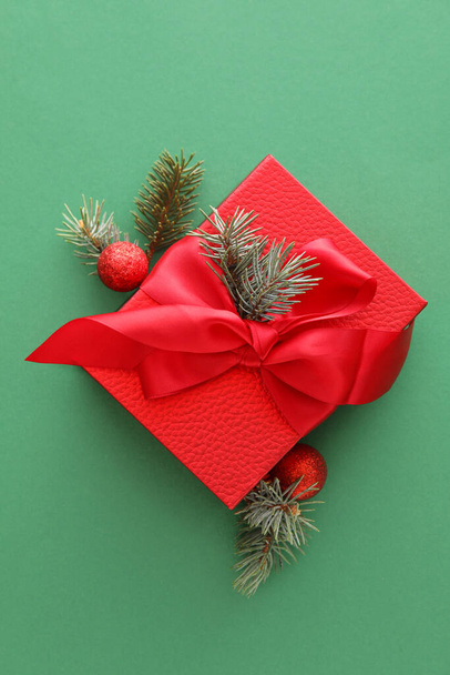 Komposition mit Weihnachtsgeschenkschachtel, Kugeln und Tannenzweigen auf grünem Hintergrund - Foto, Bild