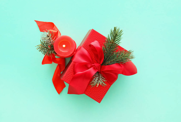 Composición con caja de regalo de Navidad, velas encendidas y ramas de abeto sobre fondo de color - Foto, imagen