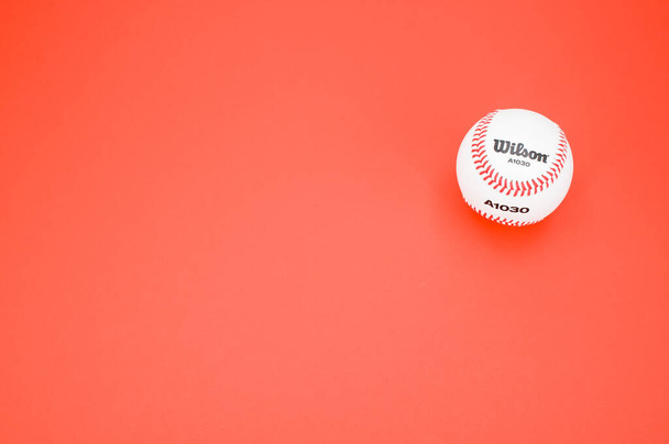 INVERIGO, ITALY - Dec 08, 2021: isolated baseball ball on a red background with text space - Fotografie, Obrázek