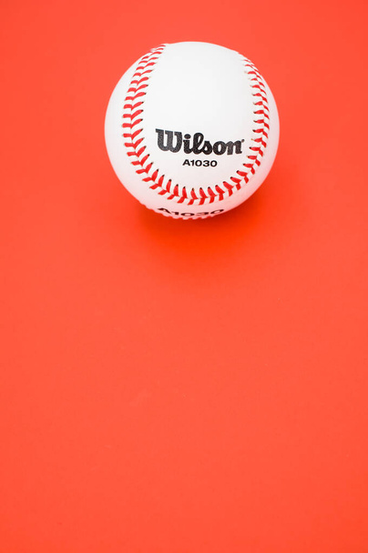 INVERIGO, ITALY - Dec 08, 2021: isolated baseball ball on a red background with text space - Φωτογραφία, εικόνα