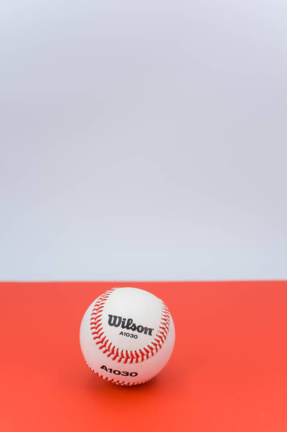 INVERIGO, ITALY - Dec 08, 2021: isolated baseball ball on a red background with text space - Fotó, kép