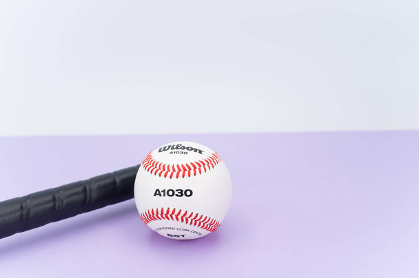 INVERIGO, ITALY - Dec 08, 2021: isolated baseball ball and bat on a lilac background with text space - Fotó, kép