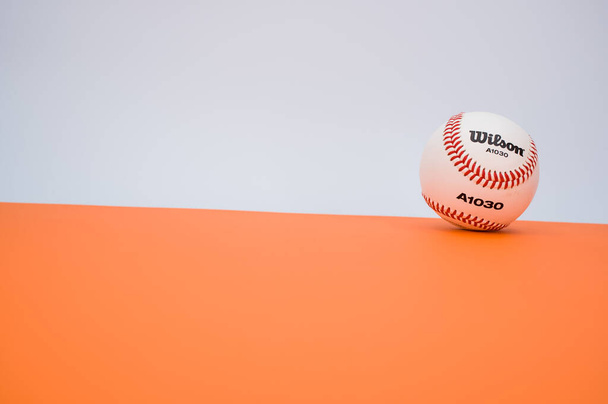 INVERIGO, ITALY - Dec 08, 2021: isolated baseball ball on orange paper background with text space - 写真・画像